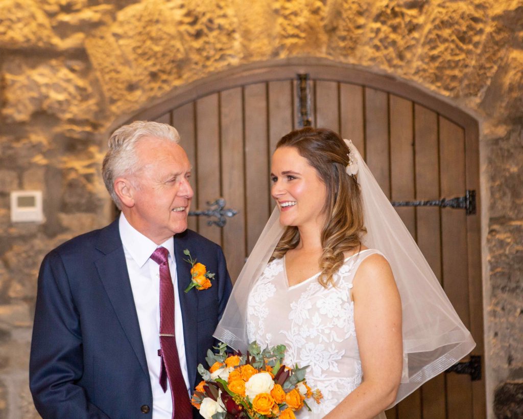 bride and her dad looking at each other smiling