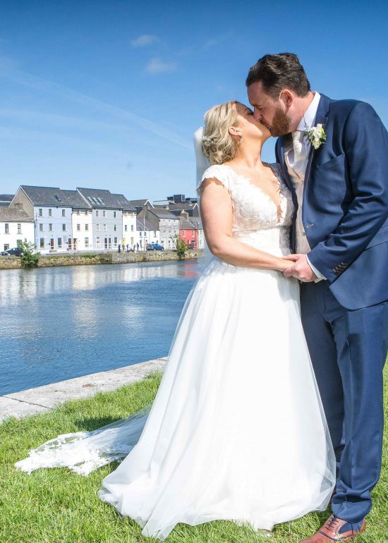 bride and groom kiss and hold hands with blue sky and blue sea