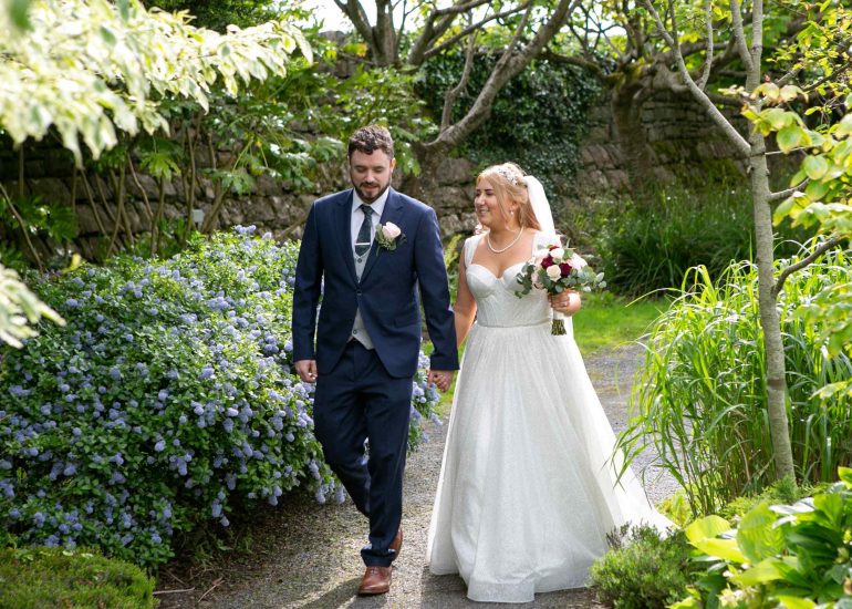 bride and groom walking toward their wedding cake admiring it