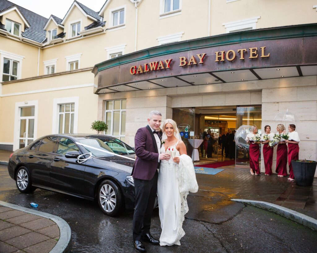 Sharon and Barry stand with drinks outside the entrance to Galway Bay Hotel on their wedding day.