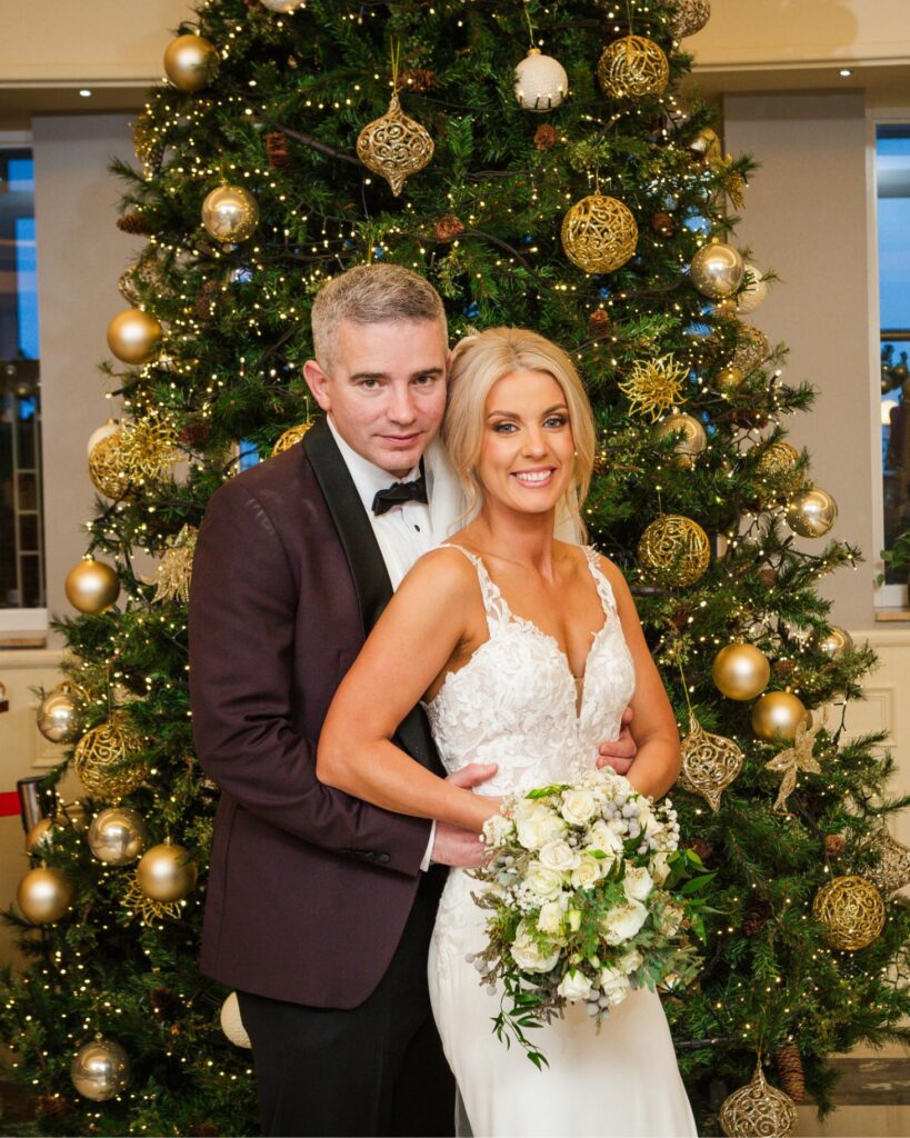 Sharon and Barry pose together in front of a decorated Christmas tree at Galway Bay Hotel.