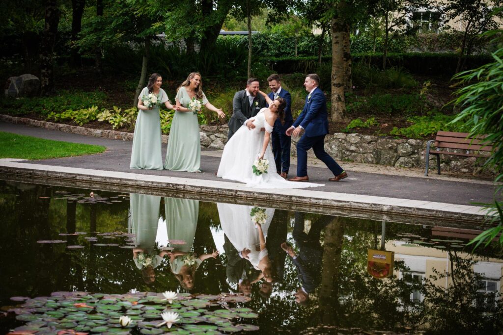 Denise and Gareth with their bridal party beside a garden pond
