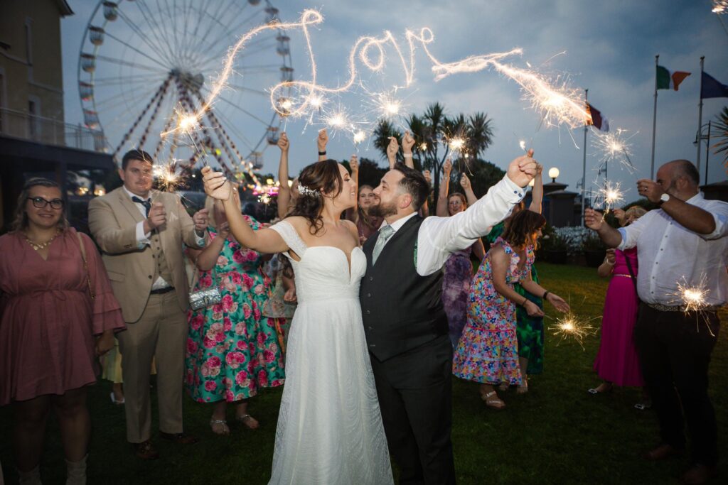 Newlyweds celebrating with guests and sparklers outside Galway Bay Hotel
