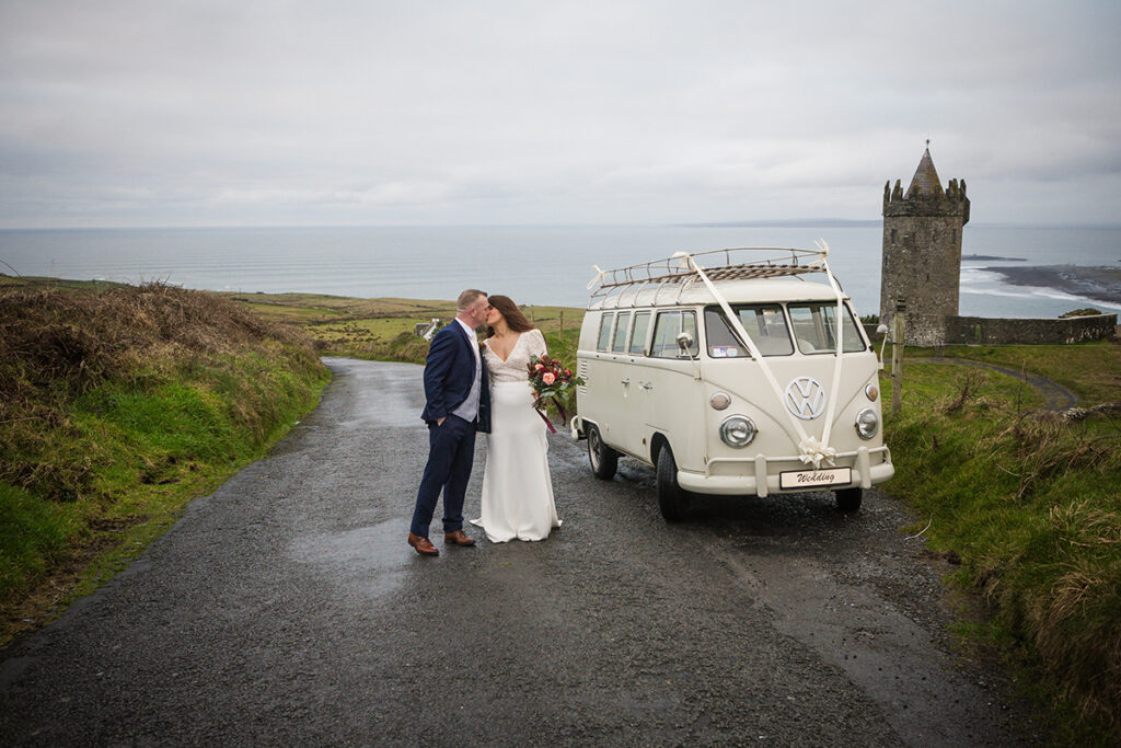 a newly married couple kissing in front of o briens tower in Doolin