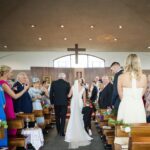 Áine walking down the aisle of Tynagh Church with her dad and a young boy beside her.
