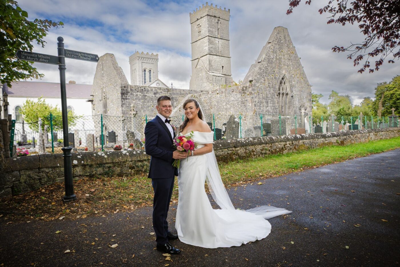Bride and groom holding a colourful bouquet outside the stone ruins of St Mary’s Abbey.