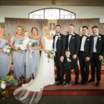 Áine and Rory posing with their bridesmaids, groomsmen and two young children at the altar of Tynagh Church.