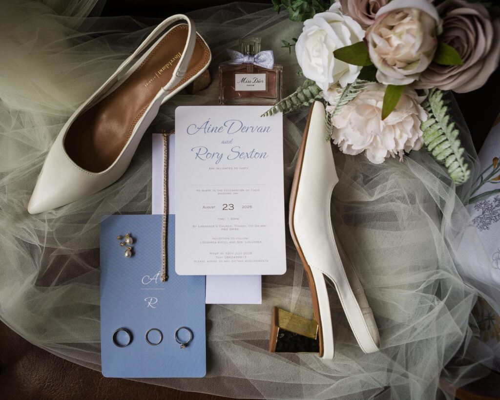 Ivory bridal shoes, pink and white bouquet, perfume and jewellery arranged on Áine’s veil.