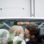 Áine and Rory kissing in their convertible outside Loughrea Hotel & Spa, with their reflection in the rear-view mirror.