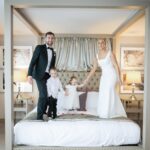 Áine and Rory standing on a four-poster bed with their two young sons at Loughrea Hotel & Spa.