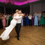 Rory lifting Áine during their first dance at Loughrea Hotel & Spa as wedding guests applaud around them.