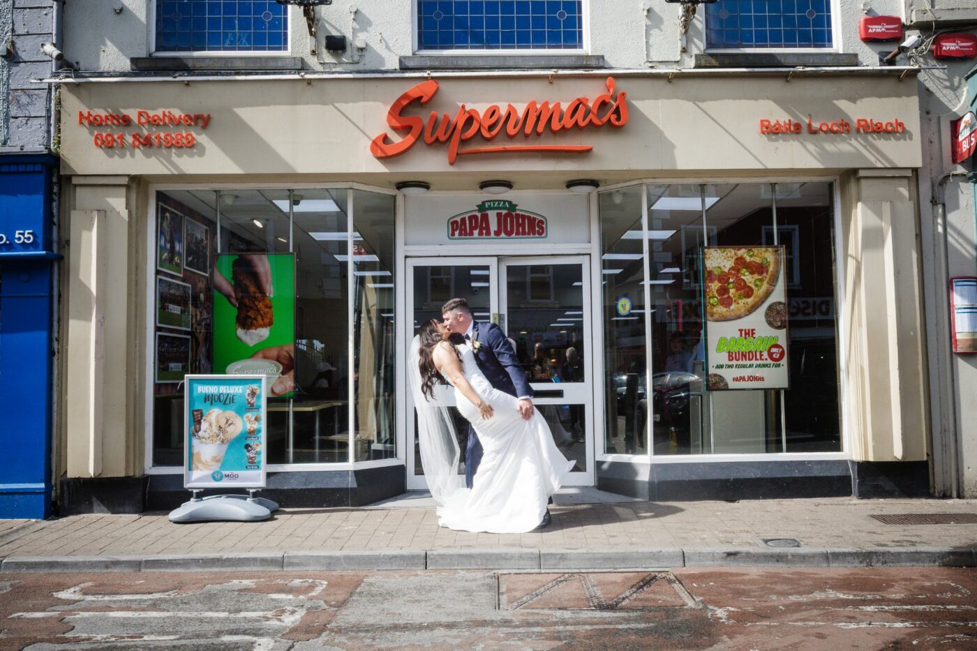 Groom dipping and kissing the bride outside Supermac’s in Loughrea.