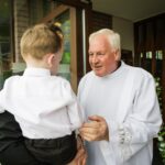 Father Bohan smiling and speaking to a young boy at the entrance to Tynagh Church.