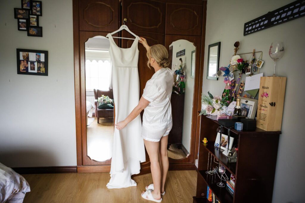 Áine looking at her wedding dress hanging in her parents’ home